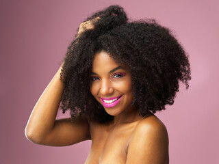 Face, hair care and happy black woman with afro in studio isolated on pink background. Hairstyle portrait, makeup cosmetics and African female model with salon treatment for beauty, growth or healthy