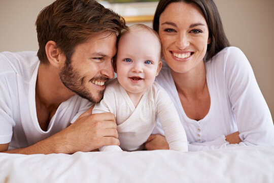 Portrait, happy family and parents with baby on bed for love, care and quality time together at home. Mother, father and newborn child relaxing in bedroom for development, caring support or happiness