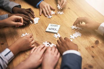 Teamwork, puzzle and hands of business people in collaboration in a meeting together planning strategy at work. Circle, professional and group in a table with synergy as a workforce for innovation