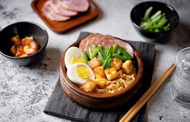 Ramen noodle with meat slices, fried Tofu, eggs and scallions in a bowl