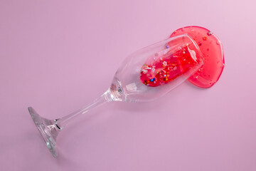 Glass with spilled liquid on pink background