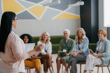 Group of mature women listening to speaker while visiting training class together