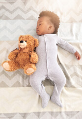 Teddy bear, bed and baby sleeping in home with lens flare for rest, nap time and dreaming in nursery. Childcare, newborn and cute, tired and African child in bedroom sleep for comfort, relax and calm