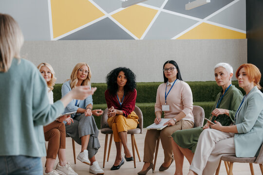 Group of confident mature women listening to speaker while visiting business conference