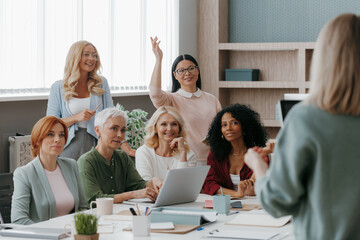 Group of mature women listening to speaker while having business training in office