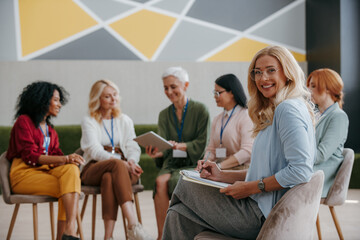 Happy mature woman looking at camera while visiting group training class for females