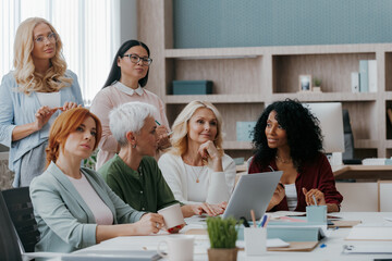 Fototapeta premium Group of mature women listening to speaker while having business training in office