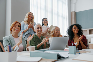 Group of mature women applauding while visiting business training class in the office
