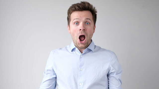 European young man is greatly surprised and opens his mouth in astonishment