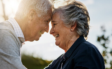 Love, nature and senior couple intimate or face together and outdoors or happy in retirement. Mature, man and woman forehead smile in vacation or senior citizens care and embrace date at the park.