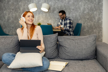 Beautiful young woman in casual clothing using laptop while working at home