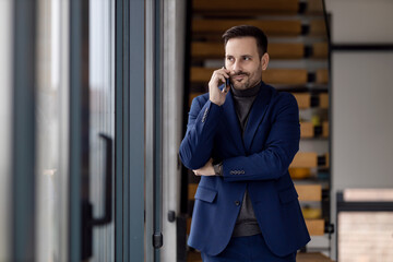 Businessman standing and using smartphone at office