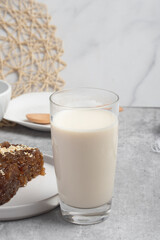 Hot fresh milk in transparent glass on gray background
