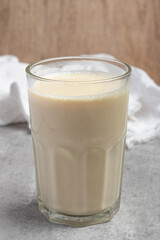 Hot fresh milk in transparent glass on gray background