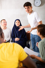 Group of multinational man and women have discussion on chairs in circle in office..