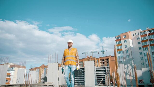 Construction worker walking and working on a construction site with a toolbox and screwdriver and high visibility clothing