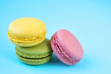Green, yellow and pink macarons on blue background