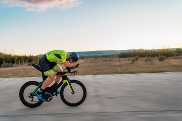  Triathlete riding his bicycle during sunset, preparing for a marathon. The warm colors of the sky provide a beautiful backdrop for his determined and focused effort.