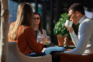 Three friends in a restaurant talking smiling and drinking tea. Business colleagues having a meeting after work or during coffee break at a cafe bar..
