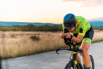  Triathlete riding his bicycle during sunset, preparing for a marathon. The warm colors of the sky provide a beautiful backdrop for his determined and focused effort.