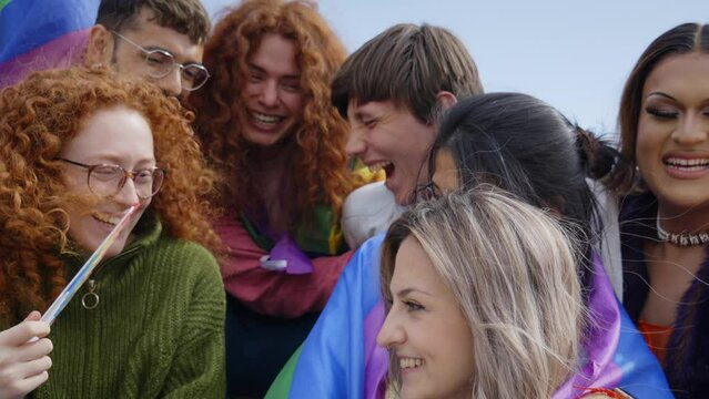Cheerful smiling diverse group of young friends together celebrating gay pride day. Happy people from the LGBT community enjoying the outdoors. Lesbian, homosexual, transgender and non binary people.