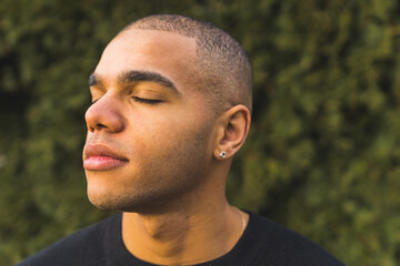 cheerful handsome guy enjoying the sun and fresh air in the park, medium closeup outdoors. High...