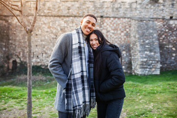 Fototapeta na wymiar Man and woman posing in front of an old stone wall. Multiracial couple in love.