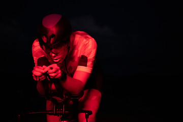 A triathlete rides his bike in the darkness of night, pushing himself to prepare for a marathon....