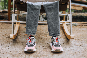 An invisible man in children's women's clothing and sneakers is resting while sitting on a rocking...