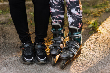 Two girlfriends are sitting on a park bench in roller skates and sneakers, preparing for sports skating. Photography, portrait, sport.