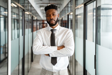 Young african american man in shirt and tie standing in office corridor