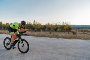  Triathlete riding his bicycle during sunset, preparing for a marathon. The warm colors of the sky provide a beautiful backdrop for his determined and focused effort.