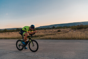 Fototapeta na wymiar Triathlete riding his bicycle during sunset, preparing for a marathon. The warm colors of the sky provide a beautiful backdrop for his determined and focused effort.