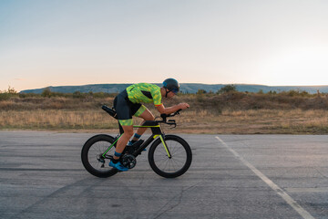 Fototapeta na wymiar Triathlete riding his bicycle during sunset, preparing for a marathon. The warm colors of the sky provide a beautiful backdrop for his determined and focused effort.