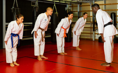 Group of athletes in kimono greet the karate trainer at the gym