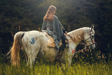 Portrait of a woman on her american native decorated white arabian horse in spring outdoors