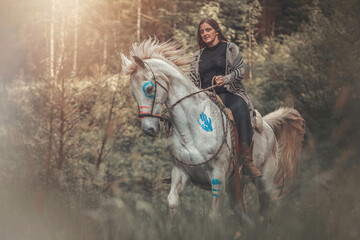 Portrait of a woman on her american native decorated white arabian horse in spring outdoors