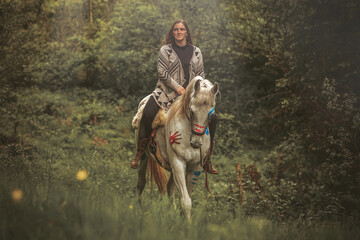 Portrait of a woman on her american native decorated white arabian horse in spring outdoors