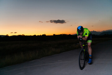 A triathlete rides his bike in the darkness of night, pushing himself to prepare for a marathon. The contrast between the darkness and the light of his bike creates a sense of drama and highlights the