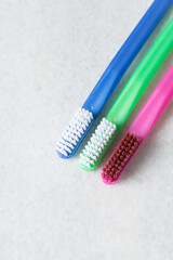 Blue, pink and green toothbrush with white bristles on a white background, colorful toothbrushes with copyspace