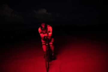 A triathlete rides his bike in the darkness of night, pushing himself to prepare for a marathon....