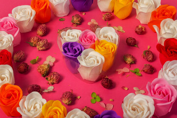 Multicolored soap roses in heart shaped gift box rounded by dried flowers and wreath of soap roses, close up. The concept of skin care, beauty, love, Valentine's Day.