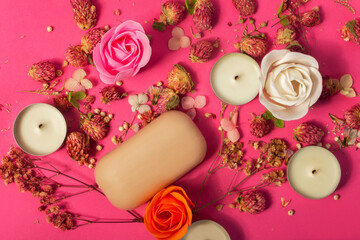 Soap making or natural relaxing spa composition with flowers, soap and candles on pink background in spa salon, top view. The concept of beauty, spa, relaxation,  soap making, heath and skin care.
