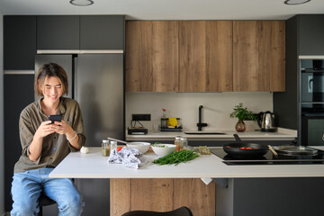 Asian young man checking recipe on mobile phone at kitchen.