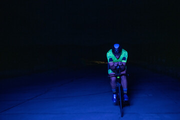 A triathlete rides his bike in the darkness of night, pushing himself to prepare for a marathon....