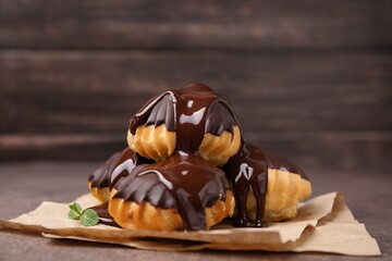 Delicious profiteroles with chocolate spread and mint on table, closeup