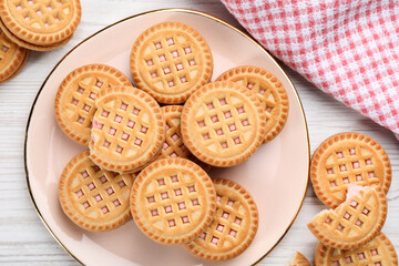Tasty sandwich cookies with cream on white wooden table, flat lay