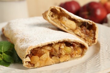 Delicious strudel with apples, nuts and raisins on plate, closeup