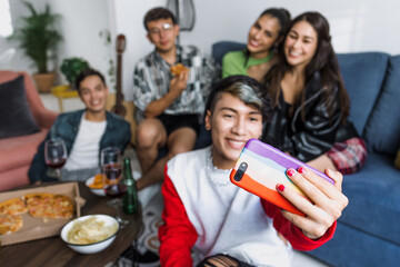 latin LGBT friends taking photo selfie with mobile phone and having fun at home in Mexico, Hispanic homosexual and lgbtq community in Latin America