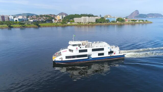 RIO DE JANEIRO, BRASIL - MAY, 2023: Drone aerial view of of Guanabara Bay, the ship is passing by. Modern and historical buildings on the shore in downtown on background at sunny day from above.